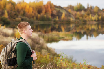 young tourist with  backpack near  autumn lake