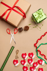 Christmas season. Wrapping Christmas gifts with gift wrapping, scissors, craft paper, cones, beads, small red mittens on a string. New Year 2020. Family holiday weekend.