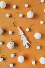 Christmas / New Year pattern with white Christmas baubles, toy fir-tree on ginger background. Flat lay, top view colorful festive holiday concept.