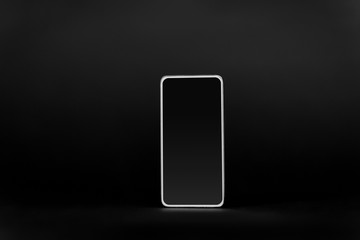 gadget, technology and electronics concept - smartphone with blank screen on black background