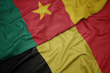 waving colorful flag of belgium and national flag of cameroon.