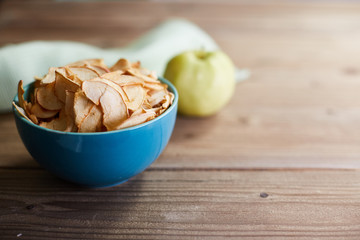 The concept of useful raw food diet. Apple chips and apple on a wooden background