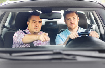 driver courses and people concept - car driving school instructor teaching young man to drive