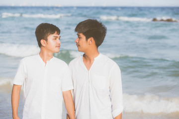 Homosexual portrait young asian couple standing together on beach in summer, asia gay holding hands going sea for leisure and relax with romantic and happy in vacation at sea, LGBT with legal concept.