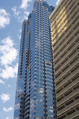 Obraz premium Blue Glass Tower by Stone Building against a blue sky