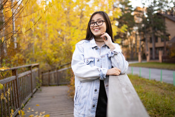 Happy young girl looking at the camera and smiling on the background of autumn nature