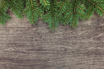 Christmas background with border of fluffy green fir branches on a textured dark brown wood