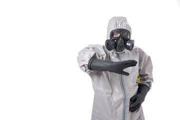 A man poses in a gray suit with a yellow radiation sign, with a protective gas mask, posing while standing on a white background.Tries to protect with his hand in his elbow.Isolated