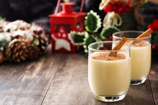 Homemade eggnog with cinnamon in glass on wooden table. Typical Christmas dessert.