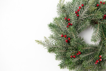 winter holidays, new year and decorations concept - wreath of fir branches with red berries on white background