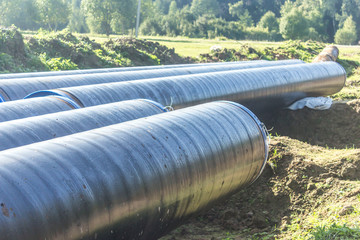 Construction of a gas pipeline laid in the ground. Black insulation.Metal pipes prepared for welding.Thousands of kilometers through rivers and taiga.