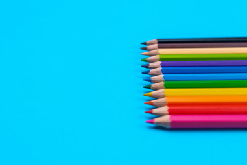 Bright colored pencils folded in a row on a blue background. Back to school. A place for writing. Stationery. Items for school and office.