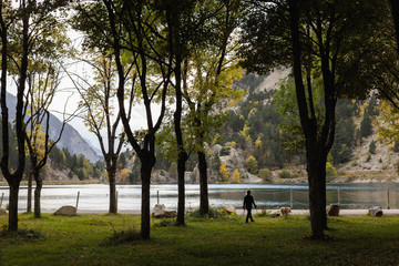 woman and dog walking in a mountain lake in autumn