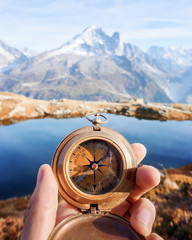 Man with compass in hand in high mountains near clear lake. Travel concept. Landscape photography - obrazy, fototapety, plakaty