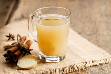 Ginger tea in a glass with fresh sliced ginger and cinnamon