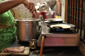 The woman standing next to stove and preparing dinner in the kitchen. Preparation of Indian food concept.