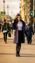 Obraz premium Beautiful serious smart brunette girl walking down street of St. Petersburg in city center. Charming thoughtful woman with long dark hair wanders alone