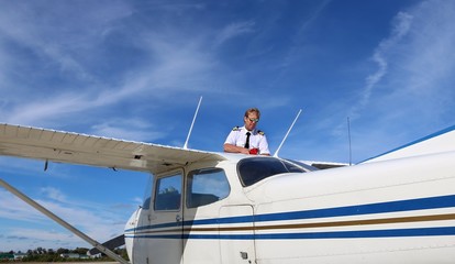 view from ground up at body of airplane with pilot in uniform filling up wings with fuel © Diane