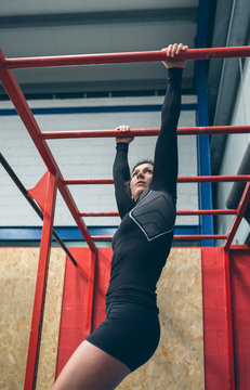 Sportswoman Exercising On Monkey Bars At The Gym