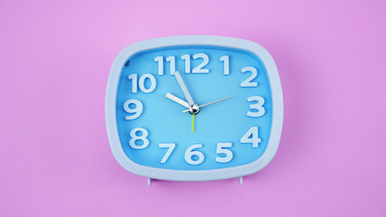 Blue alarm clock on pink background, Copy space for your text, Time concept.