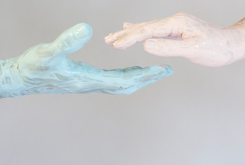 Male and female hand in blue and pink paint holding each other