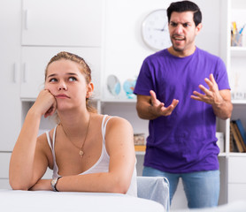 Obraz premium Frustrated girl at table with angry boyfriend