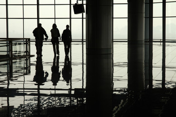 Fototapeta na wymiar Silhouetted travellers in an airport terminal