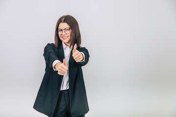 Lovely young businesswoman in black suit standing, giving thumbs up, smiling enticingly.