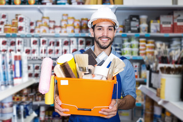 Positive guy worker holding basket with tools