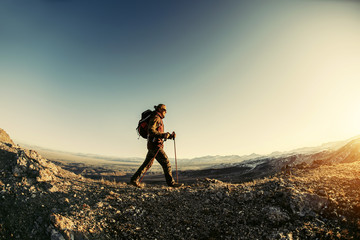 Hiker walks in sunset mountains