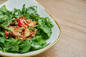 Close up view on tasty Light warm salad with tomato, turkey, a mix of greens in stylish grey bowl. Tasty lunch. Wooden background