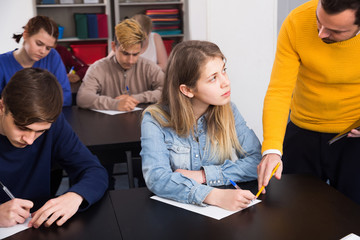 Male teacher clearing up complicated issue to pupil during exam in class