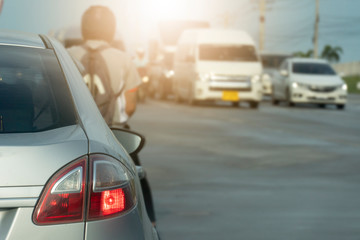 Luxury of silver car stop on the asphalt junction by traffic light control in across. Traveling in the provinces during the bright period. Open light brake. With blurred motorcyclist in the front.