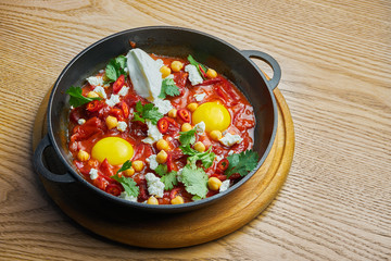Close up view on shakshuka with hot chili pepper in tomato juice with the addition of chickpea, cheese and bell pepper. Traditional Israeli Cuisine