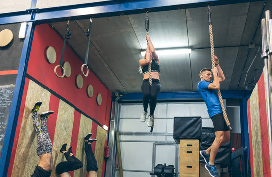 Group training climbing rope and doing headstands at the box