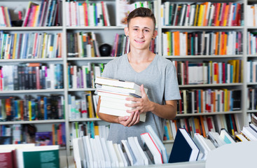 Portrait of laughing teenager boy with book pile