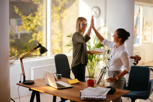Two young colleagues giving each other a high five