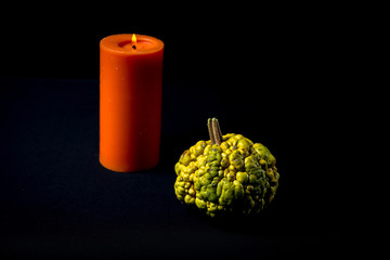 Decorative Green Warty Pumpkin With Red Candle On Black Background