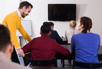 Male teacher clearing up complicated issue to pupil during exam in class