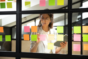 Businesswoman creates priority to-do list on sticky notes - obrazy, fototapety, plakaty