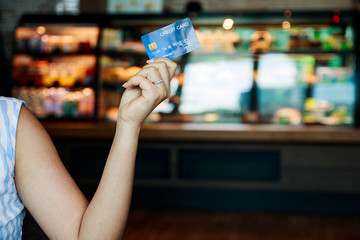 Asian woman hand holding a credit card in a coffee shop