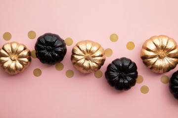 Gold and black pumpkins on pastel pink. Flat lay thanksgiving composition