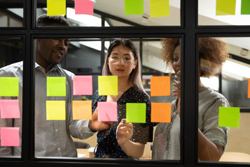 Diverse colleagues writing on sticky notes new project plan