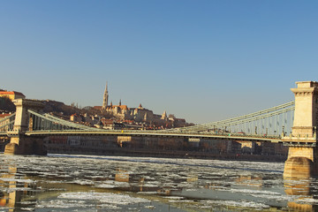 Stunning winter landscape of Chain Bridge across the River Danube. Medieval Fisherman's Bastion on a hill in the background. Famous touristic place and romantic travel destination