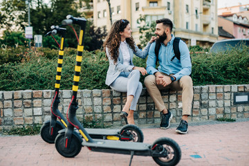 Happy young couple with electric scooters.