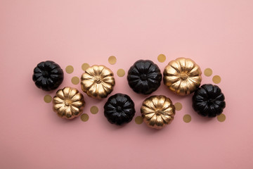 Gold and black pumpkins on pastel pink. Flat lay thanksgiving composition