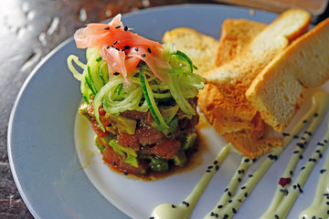 Plate of raw tuna poke with fresh avocado and pickled ginger