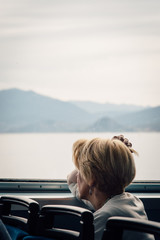 une femme mature et âgée regardant par la fenêtre d'un train ou d'un bateau.