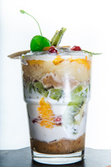 vertical view on healthy fruits and cream dessert in tall glass