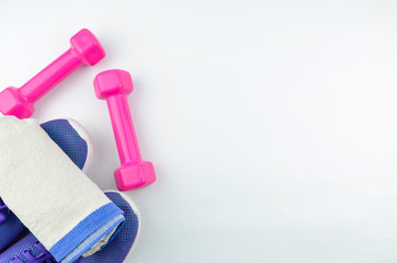 Fitness concept background with sneakers, dumbbells and towel. Top view with space for your text.